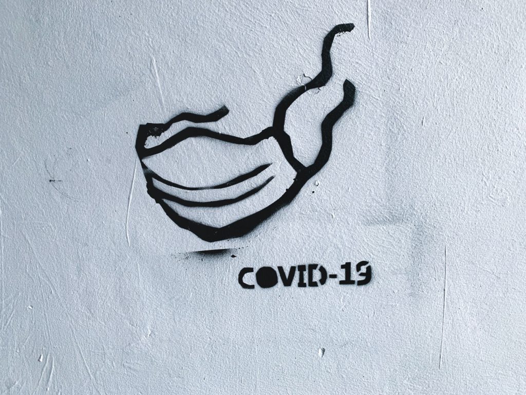 Black and white graffiti of face mask with COVID-19 written beneath. National institutes of health.