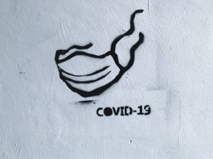 black and white graffiti of face mask with COVID-19 written beneath