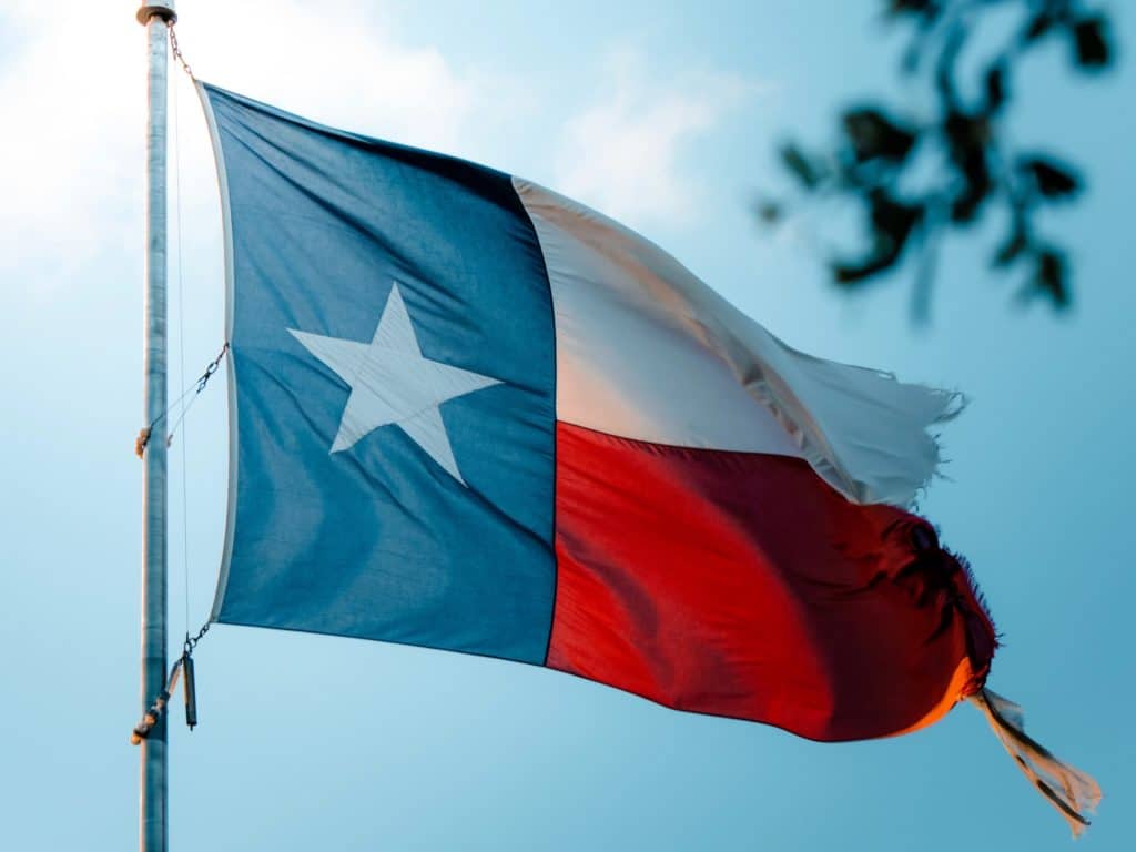 Texas flag flying in the wind against a lovely blue sky